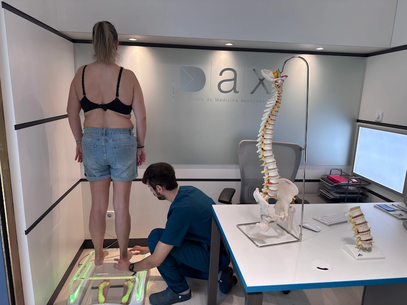 Fisioterapeuta realizando análisis postural personalizado con plataforma de valoración biomecánica para diagnóstico individual.